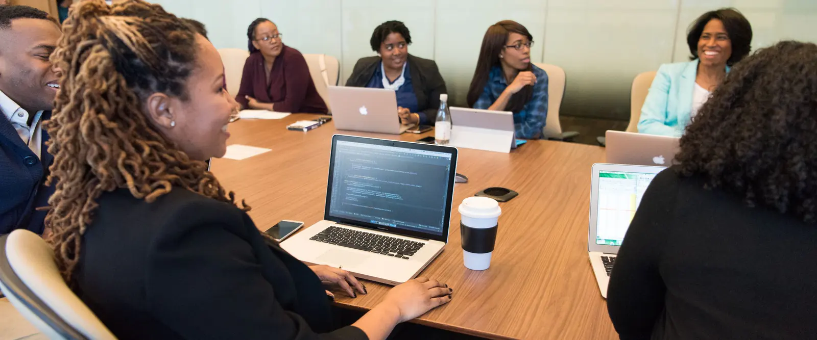 Cohorte de dirigeants réunis autour d'une table de réunion, ordinateurs portables ouverts