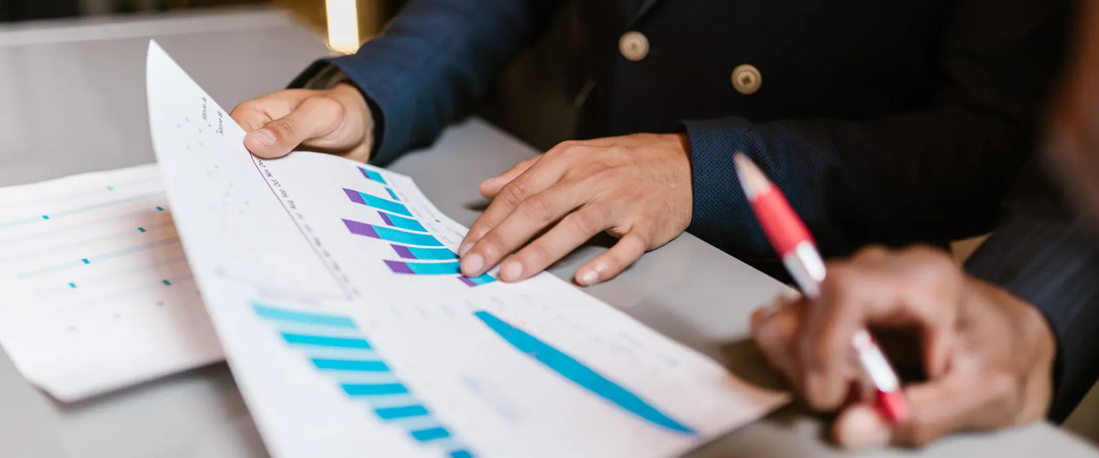 Mains de consultants annotant au crayon des graphiques imprimés lors d'un audit