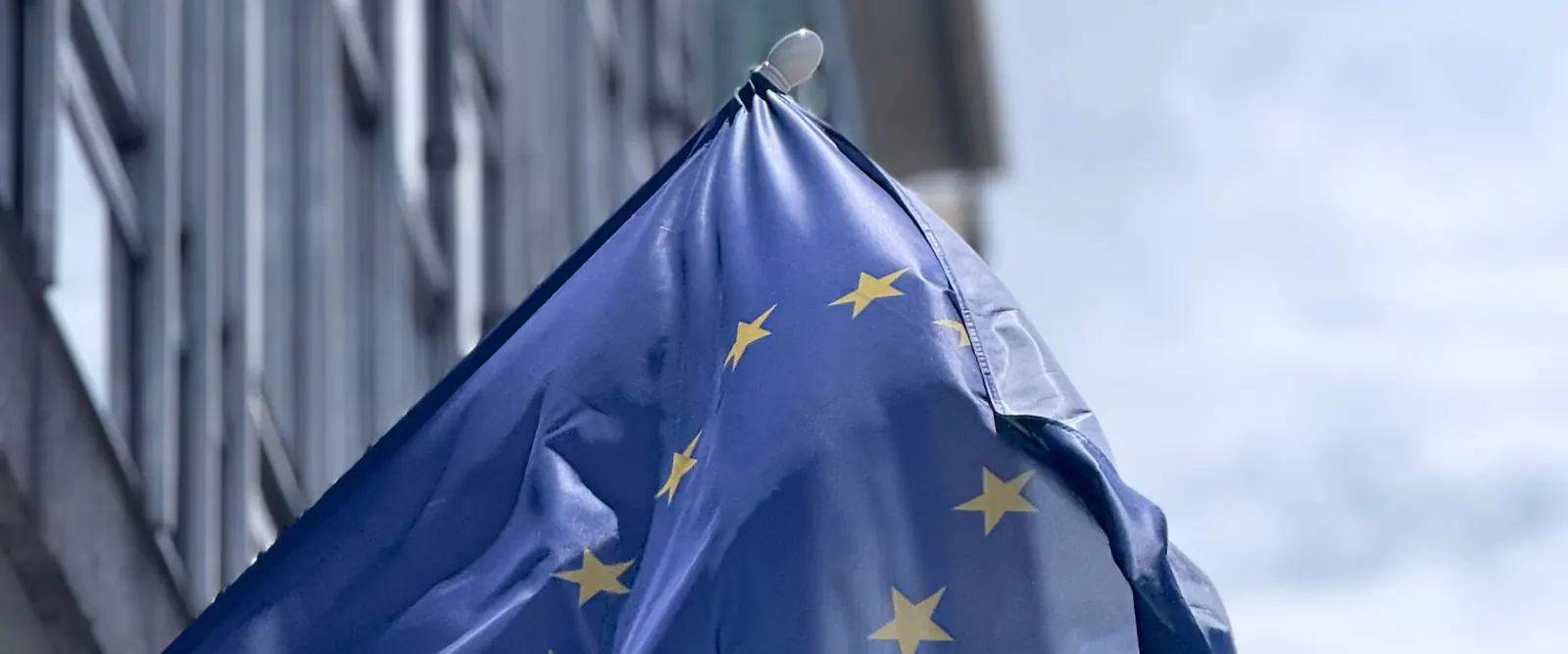Drapeau européen flottant devant la façade vitrée d'un bâtiment institutionnel à Bruxelles