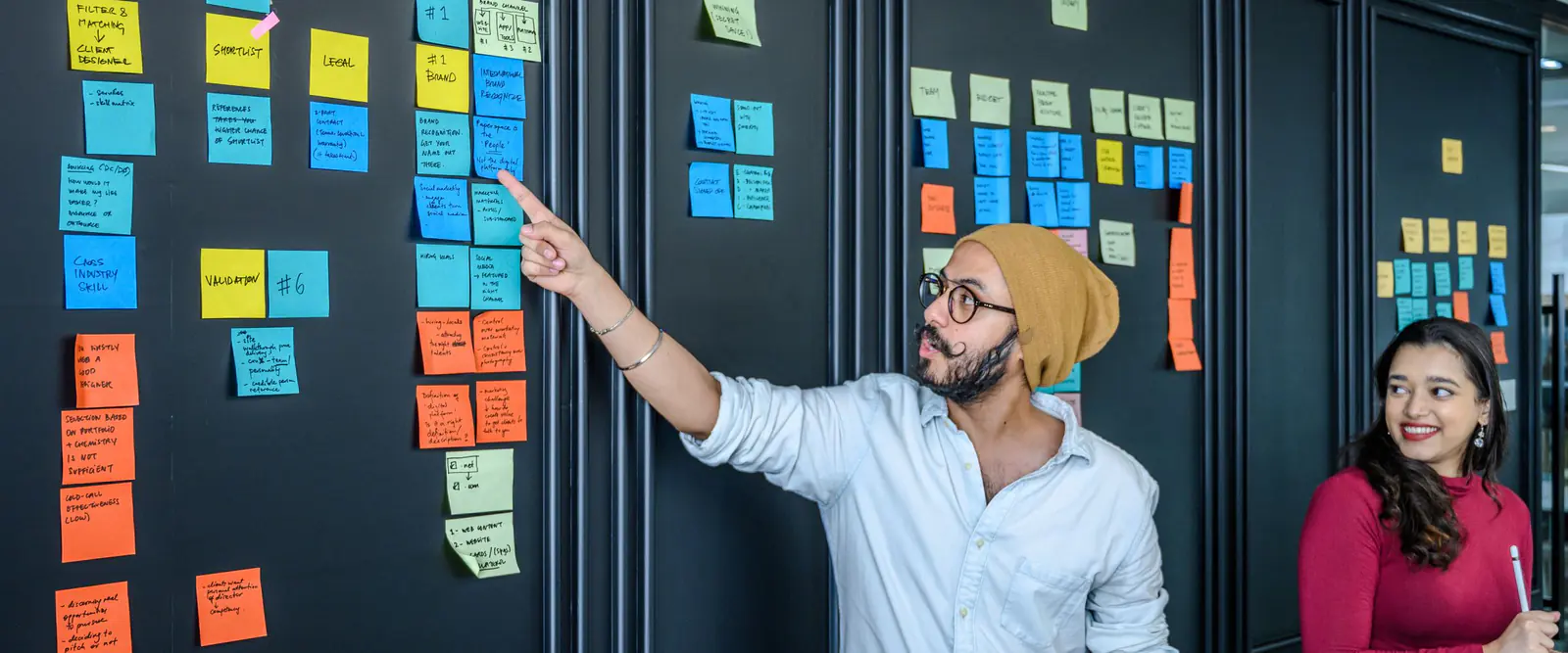 Atelier de priorisation : un intervenant désigne des post-it organisés en colonnes sur un mur